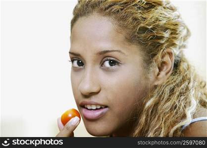 Close-up of a young woman holding a cherry in front of her mouth