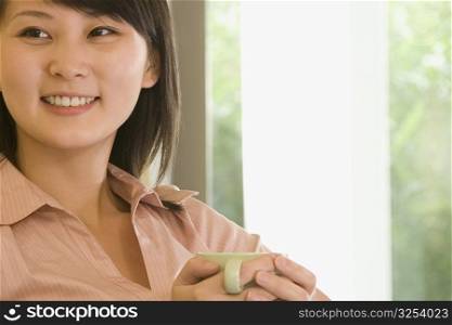 Close-up of a young woman holding a coffee cup and smiling