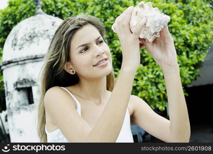 Close-up of a young woman holding a conch shell