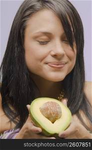 Close-up of a young woman holding a cross section of an avocado