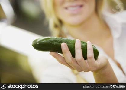 Close-up of a young woman holding a cucumber