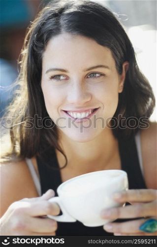 Close-up of a young woman holding a cup and smiling