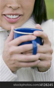 Close-up of a young woman holding a cup of coffee and smiling