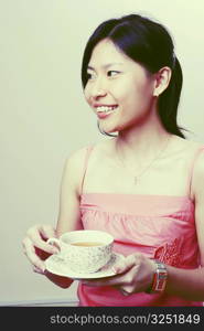 Close-up of a young woman holding a cup of tea and smiling