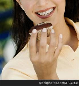 Close-up of a young woman holding a cupcake and smiling