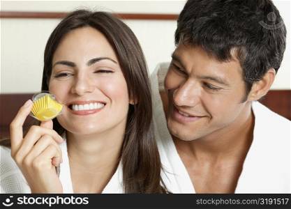 Close-up of a young woman holding a cupcake with a mid adult man looking at her