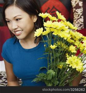 Close-up of a young woman holding a flower vase and smiling