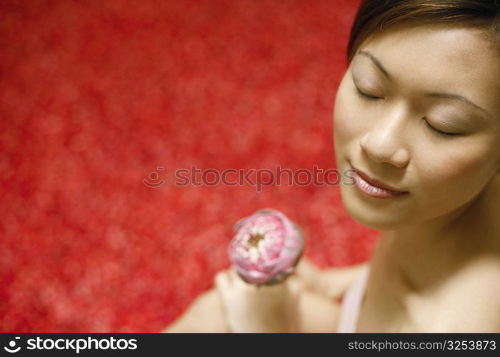 Close-up of a young woman holding a flower with her eyes closed