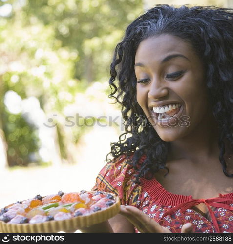 Close-up of a young woman holding a fruit tart