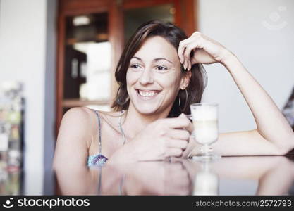 Close-up of a young woman holding a glass of coffee and smiling