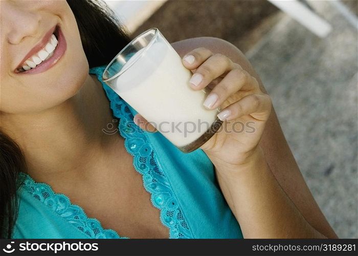 Close-up of a young woman holding a glass of milk and smiling