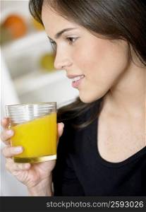 Close-up of a young woman holding a glass of orange juice and smiling