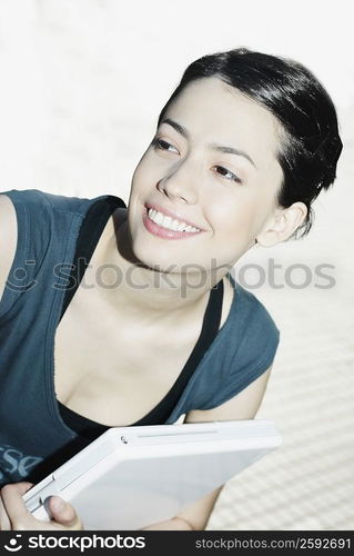 Close-up of a young woman holding a laptop and smiling