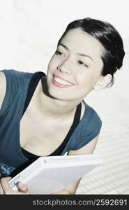 Close-up of a young woman holding a laptop and smiling