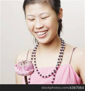Close-up of a young woman holding a lotus flower and smiling