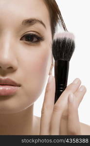 Close-up of a young woman holding a make-up brush