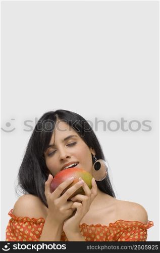 Close-up of a young woman holding a mango