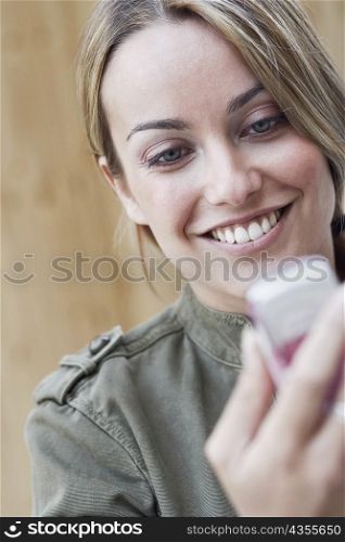 Close-up of a young woman holding a mobile phone and smiling