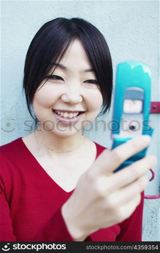 Close-up of a young woman holding a mobile phone and smiling
