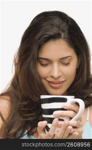Close-up of a young woman holding a mug of coffee and smiling