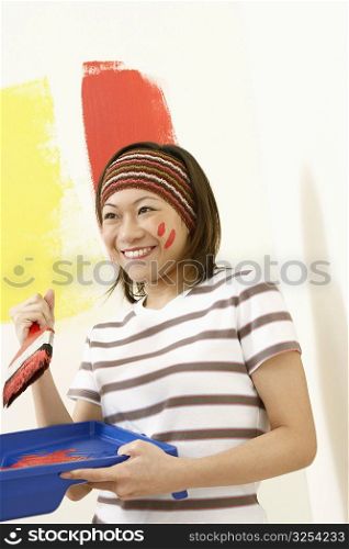Close-up of a young woman holding a paint tray and a paintbrush