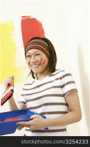 Close-up of a young woman holding a paint tray and a paintbrush