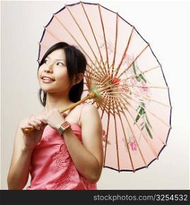 Close-up of a young woman holding a parasol and looking away
