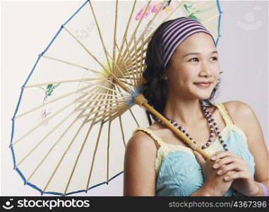 Close-up of a young woman holding a parasol and smiling