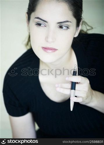 Close-up of a young woman holding a pen