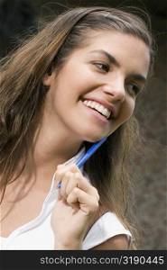 Close-up of a young woman holding a pen and smiling