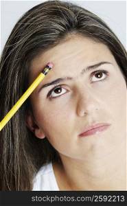 Close-up of a young woman holding a pencil and thinking