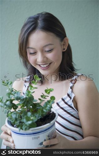 Close-up of a young woman holding a potted plant and smiling
