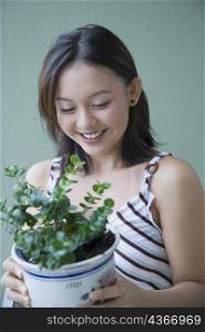 Close-up of a young woman holding a potted plant and smiling