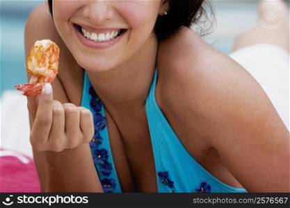 Close-up of a young woman holding a prawn and smiling