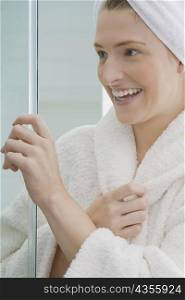 Close-up of a young woman holding a screen door and smiling