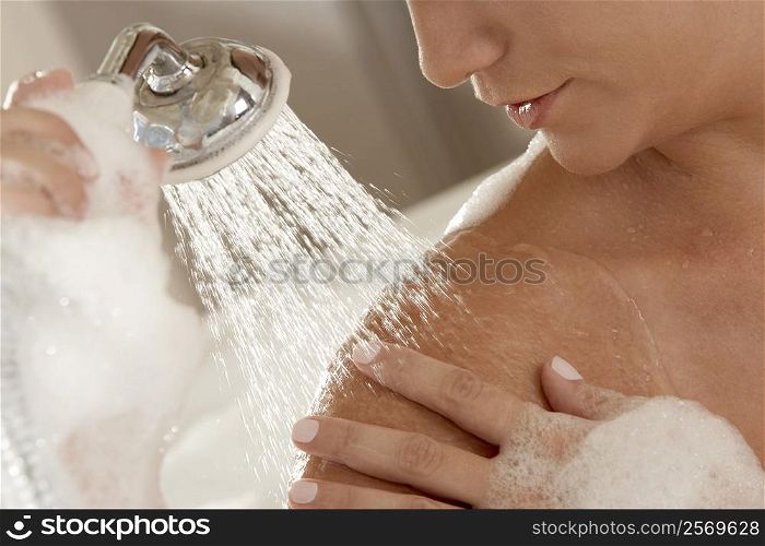 Close-up of a young woman holding a shower head