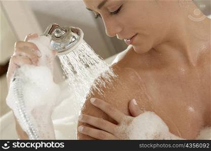 Close-up of a young woman holding a shower head