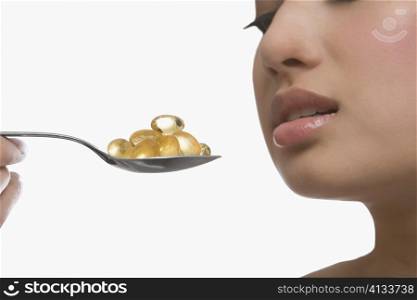 Close-up of a young woman holding a spoon of pills