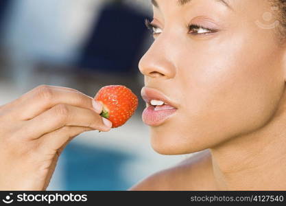 Close-up of a young woman holding a strawberry