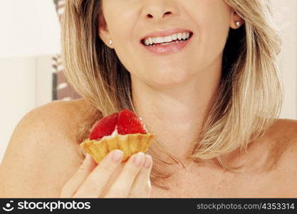 Close-up of a young woman holding a strawberry tart