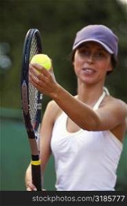 Close-up of a young woman holding a tennis ball and a tennis racket