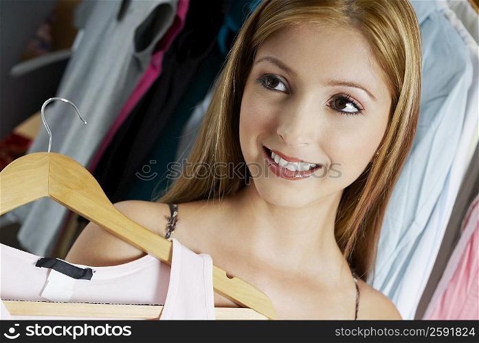 Close-up of a young woman holding a top on a hanger