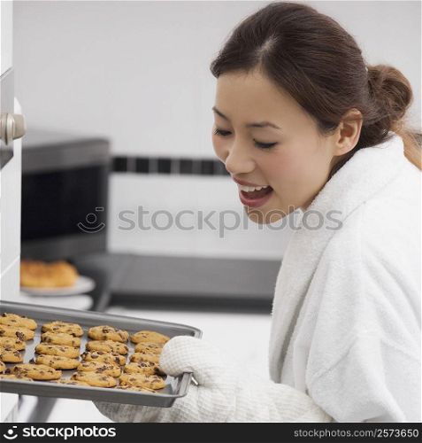 Close-up of a young woman holding a tray of cookies and smiling