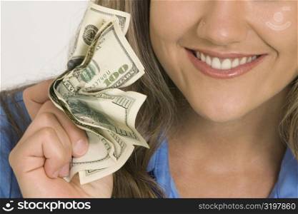 Close-up of a young woman holding American paper currency and smiling