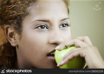 Close-up of a young woman holding an apple in front of her mouth