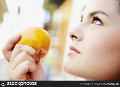 Close-up of a young woman holding an orange