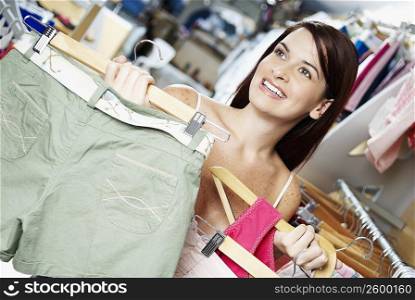 Close-up of a young woman holding clothes on a hanger in a clothing store