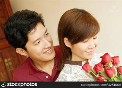 Close-up of a young woman holding flowers with a young man