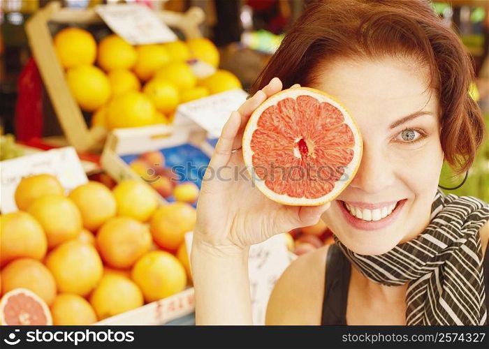 Close-up of a young woman holding half a grape fruit