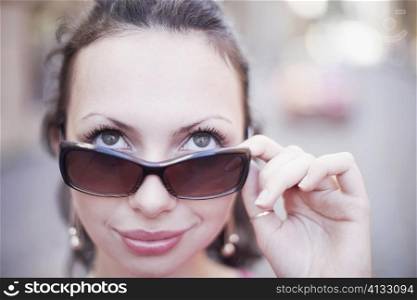 Close-up of a young woman holding sunglasses